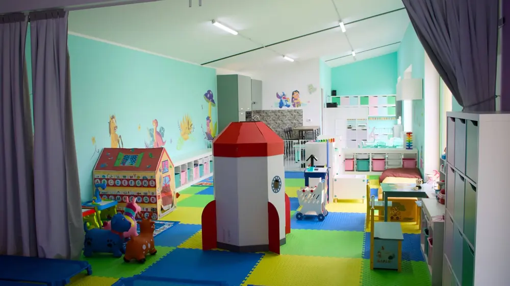 Bambini che giocano con costruzioni e materiali morbidi in uno spazio educativo